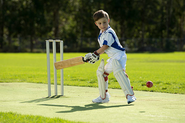 A young boy batting while playing cricket